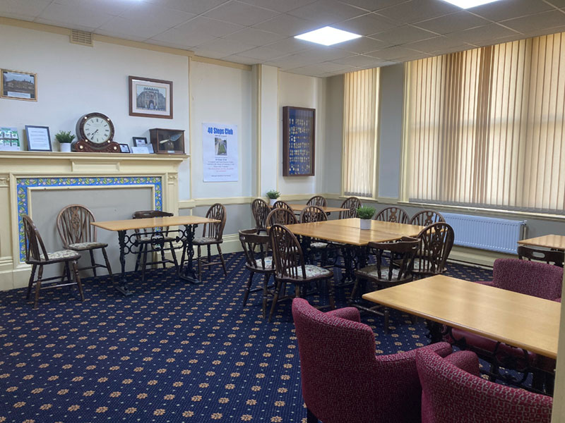 The bar lounge with wooden tables, wheelback chairs and a tiled fireplace